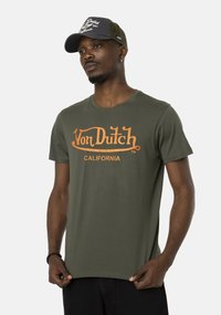 Camiseta de algodón verde oliva con el logo naranja de "Von Dutch" y el texto "CALIFORNIA". Mangas cortas y cuello redondo, textura de tela suave.