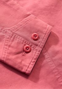 Col haut en coton rose avec deux boutons assortis, couture visible et finition en tissu texturé.