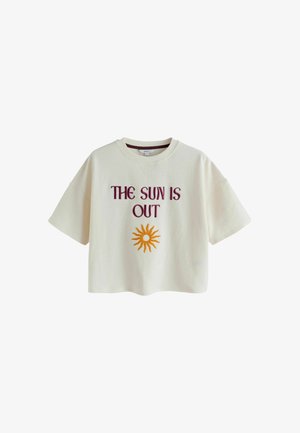 Kremowy krótki T-shirt z krótkimi rękawami, z bordowym napisem „THE SUN IS OUT” i małą pomarańczową grafiką słońca poniżej.