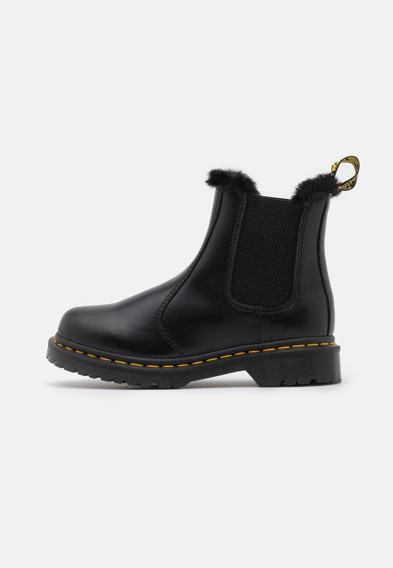 Zwarte leren enkelboots met textuur in de elastische zijpanelen, een bontafwerking aan de bovenkant, gele stiksels en een stevige rubberen zool.