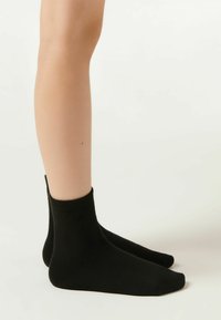 Calzini neri alla caviglia realizzati in materiale a maglia liscia con un bordo a coste, caratterizzati da una vestibilità aderente e un design minimalista.