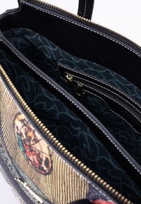 Black leather tote bag with a textured exterior and gold zipper. Interior features a patterned fabric lining and multiple compartments.