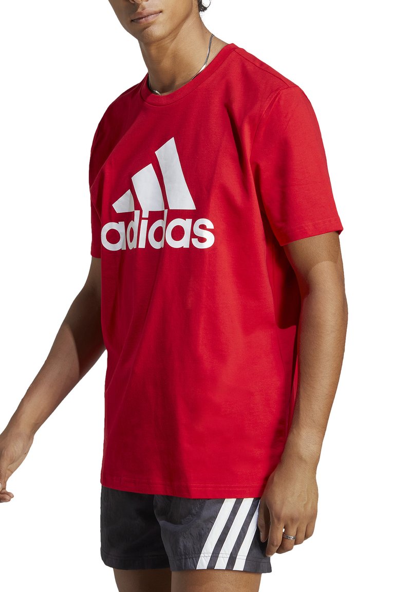 T-shirt di cotone rosso con un grande logo Adidas bianco. Maniche corte, scollo rotondo e una vestibilità rilassata con colore uniforme.