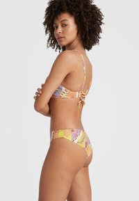 Bikini in mehreren Farben mit einem gemusterten Oberteil, verstellbaren Trägern und gebundenem Rücken, kombiniert mit passendem, niedrig geschnittenem Unterteil. Glatte Textur.