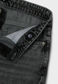 Vaqueros de mezclilla gris oscuro con un acabado texturizado, que presentan un cierre con botón y un pequeño bolsillo frontal. Forro visible en el interior de la cintura.