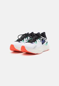 Athletic shoes featuring a predominantly white mesh upper, black laces, green and purple accents, and a red rubber sole for traction.
