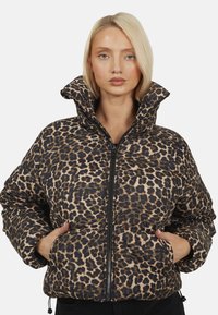 Kurtka puchowa w panterkę z wysokim kołnierzem, zamkiem z przodu i elastycznymi mankietami. Charakteryzuje się błyszczącym materiałem o teksturowej powierzchni.