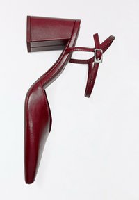 Sandale à talon bloc en cuir rouge foncé pour femme avec bride de cheville et boucle argentée, bout pointu et design épuré minimaliste.