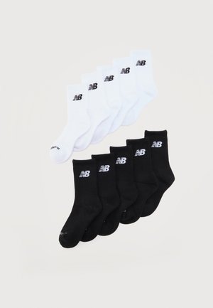 Vijf paar witte en vijf paar zwarte crew sokken met New Balance-logo, gestapeld op een eenvoudige lichte achtergrond.