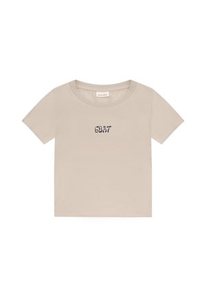 Beiges kurzärmeliges, cropped T-Shirt mit rundem Ausschnitt und dem Wort "GOAT", das in Schwarz mittig auf der Vorderseite gedruckt ist.
