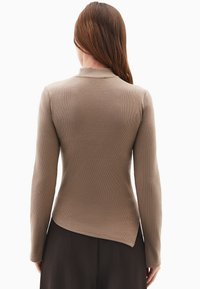 Długi rękaw, dopasowany top w taupe’owym prążkowanym materiale z subtelnym wykończeniem w stylu high-low. Posiada okrągły dekolt i miękką fakturę.