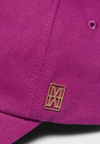 Roze pet van textuurstof met een gouden metalen logoaccent. De cap heeft een gebogen rand en bijpassende stikdetails.