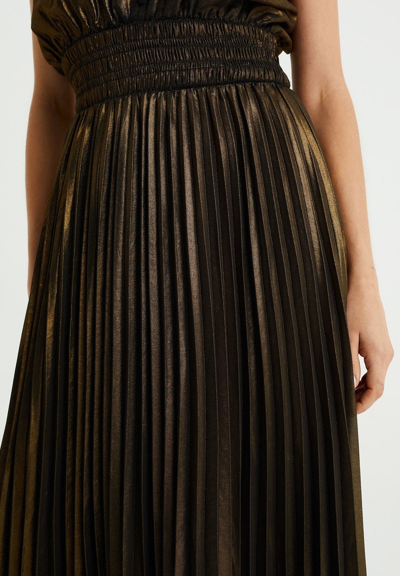 Zwarte geplooide jurk met een glanzende afwerking, met een smock tailleband en verticale plooien die van de taille naar de zoom vloeien.