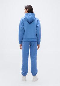 Ανοιχτό μπλε φούτερ με κουκούλα και ταιριαστά τζόγκερ από μαλακό ύφασμα, με κουκούλα, ριμπ μανσέτες και στενές ανοίγματα στα πόδια.
