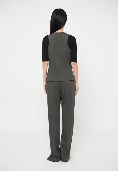 Sivý strihaný top s čiernym krátkym rukávom pod ním, spojený so sivými širokými nohavicami. Hladká textúra, elegantný dizajn, čisté línie.