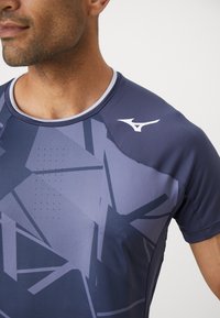 Tricou sportiv navy cu un model geometric, textură netedă, material respirabil și un logo alb pe umăr.