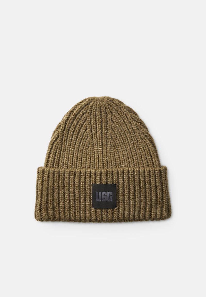 Beanie tricotat de culoare verde măsliniu, cu o textură cu nervuri, având un eticheta rectangulară neagră cu logo-ul „UGG” pe față.