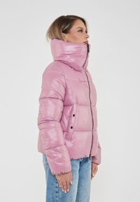 Giacca a vento rosa con colletto alto, zip frontale e due tasche laterali. Presenta una finitura lucida e una texture trapuntata.