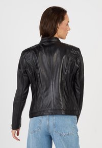 Zwarte leren motorjack met een tekstuur op de schouderaccenten, een slim-fit silhouet en ritsmanchetten. Glad oppervlak met naaddetails.
