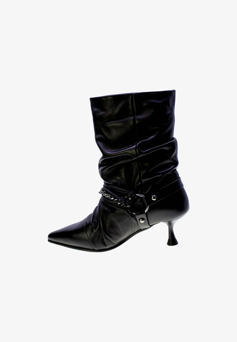 Stivale alla caviglia in pelle nera con design morbido, punta affusolata e tacco alto slim. Presenta un accento a catena attorno alla caviglia con un dettaglio in fibbia.