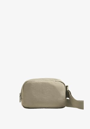 Sac bandoulière en tissu beige avec une forme rectangulaire, une fermeture éclair et une sangle ajustable pour des options de transport polyvalentes.