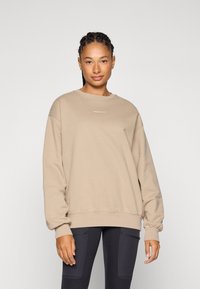 Beige sweatshirt van een zacht materiaal met een ontspannen pasvorm, ronde hals en ribgebreide manchetten. Met subtiele merklogo op de borst.