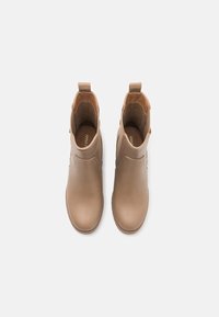 Botas de tobillo de cuero marrón claro con un acabado suave, paneles laterales elásticos y asas de tirón. El interior cuenta con un forro suave y una forma estructurada.