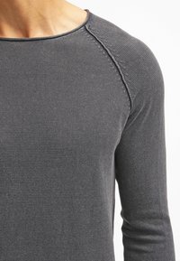 Chemise à manches longues gris foncé en tissu texturé et côtelé. Comprend un col rond et des coutures détaillées le long des coutures d'épaule.