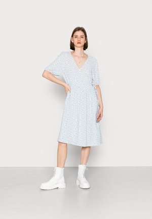 Vestido azul claro com decote em V, mangas curtas e cintura ajustada. Apresenta um padrão floral e termina na metade da panturrilha. Usado com botas brancas.