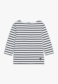 Chemise à manches longues rayée en blanc et noir avec un col bateau et un écusson à logo bleu marine. En coton, coupe décontractée, et ourlet plat.