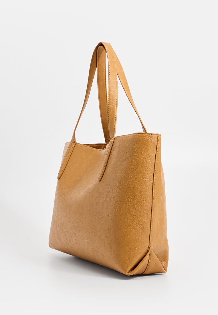 Sac fourre-tout en cuir tan avec une texture lisse, de forme rectangulaire et deux longues sangles pour les épaules. Présente un design minimaliste sans embellissements.