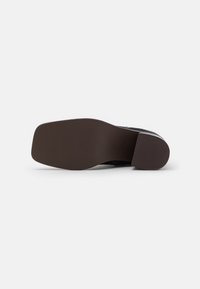 Suela de zapato de cuero negro con forma lisa y redondeada y fondo de goma marrón. Presenta un diseño minimalista sin patrones o acentos destacados.