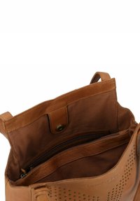 Borsa tote in pelle marrone con accenti perforati, tasca con zip e fodera in tessuto. Presenta una chiusura a moschettone magnetica e manici doppi.