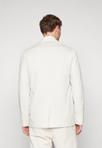 Hvit lin blazer med avslappet passform, skjulte slag og en enkelt ventil bak. Har lange ermer og et rent, minimalistisk design.