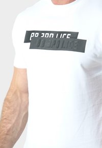 Witte katoenen T-shirt met een gedurfde zwarte grafische tekstontwerp met overlappende rechthoekige vormen, met de tekst "88 3PO LICE."