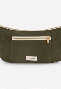 Sac en tissu vert olive à forme incurvée, avec une fermeture éclair dorée et une poche avant. Présente un écusson logo visible avec le nom de la marque.