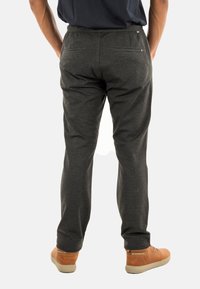 Pantaloni jogger grigi con cintura elastica, tasche posteriori e gambe affusolate, abbinati a scarpe marroni. Tessuto morbido e liscio.