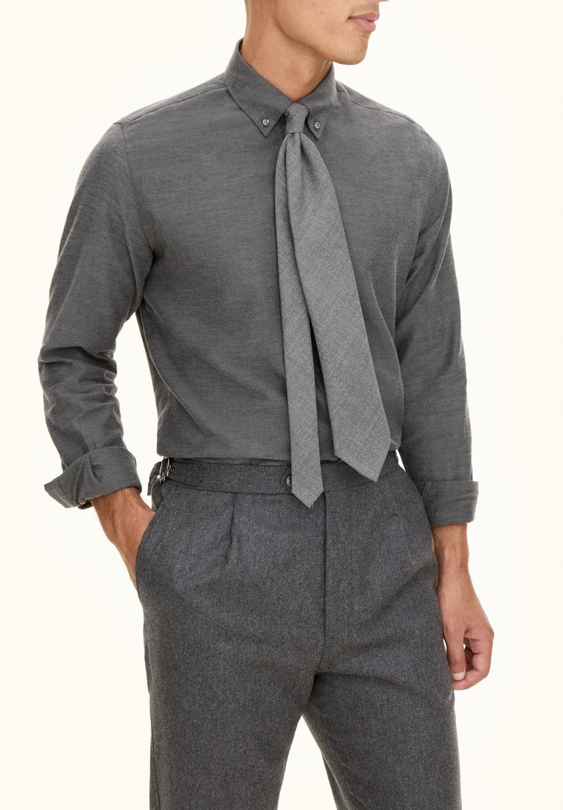 Grijze button-up overhemd met een textuurstof en een stropdas. Gecombineerd met grijze op maat gemaakte broeken, die een klassieke pasvorm en nette details tonen.