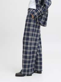 Calças largas de padrão xadrez em azul-marinho e branco, com cintura elástica, fabricadas com um tecido texturizado e um ajuste solto, combinadas com botins pretos de salto.