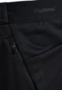 Svarta träningsbyxor med en slät yta, utrustade med en ficka med dragkedja och en resårmidja med varumärket "hummel".