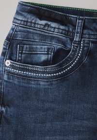 Tmavě modré denimové džíny s klasickým pětipocketovým designem, kontrastním prošíváním a jemnými efekty vyblednutí na pásku a okrajích kapes.