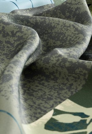 Kangas with an abstract pattern featuring shades of green and gray. Pehmeä, teksturoitu kangas taitettuna, jotta erilaiset värit ja muotoiluelementit paljastuvat.