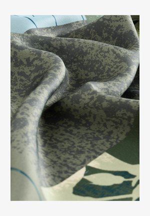 Absztrakt mintázatú textil, zöld és szürke árnyalatokkal. Puha, struktúrált anyag, amelyet összehajtva változatos szín- és dizájn részletek tárulnak fel.