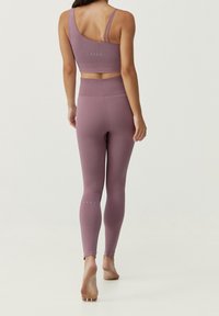 Lila träningsset som innehåller en figurnära, ribbad crop top med justerbara remmar och högmidjade leggings med accentstygning vid fållen.