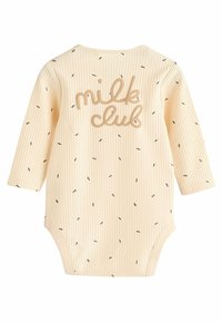 Crème ribbel onesie met lange mouwen, voorzien van de tekst "milk club" in beige en verspreide donkere stippen door de stof.