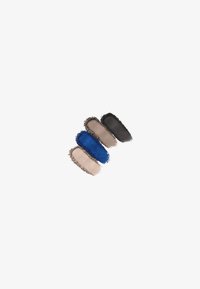 Échantillons de couleurs cosmétiques en quatre formes courbées : bleu foncé, marron clair, taupe et noir, avec des textures douces et un fini mat.