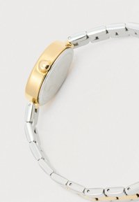 Guldtonet rundt urkasse med sølvtonet metallarmbånd. Glat finish med en fremtrædende krone og en klar urskive.