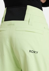 Ljusgröna byxor med svart midjeband, med två bakfickor och Roxy-logotyp i svart broderi på höger ficka.