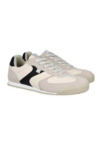 Zapatillas deportivas en beige y negro, confeccionadas con materiales de ante y malla, que presentan un diseño de cordones y una suela de goma texturizada. Decoradas con un logo.