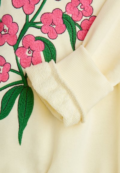 Sweatshirt amarelo com vibrante bordado floral em rosa, acentos de folhas verdes e punhos texturizados com bordas caneladas. Tecido macio.